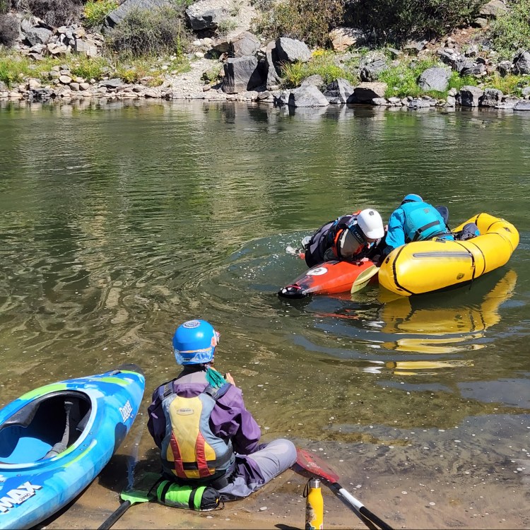 Photo of a person being assisted in getting back into their kayak.